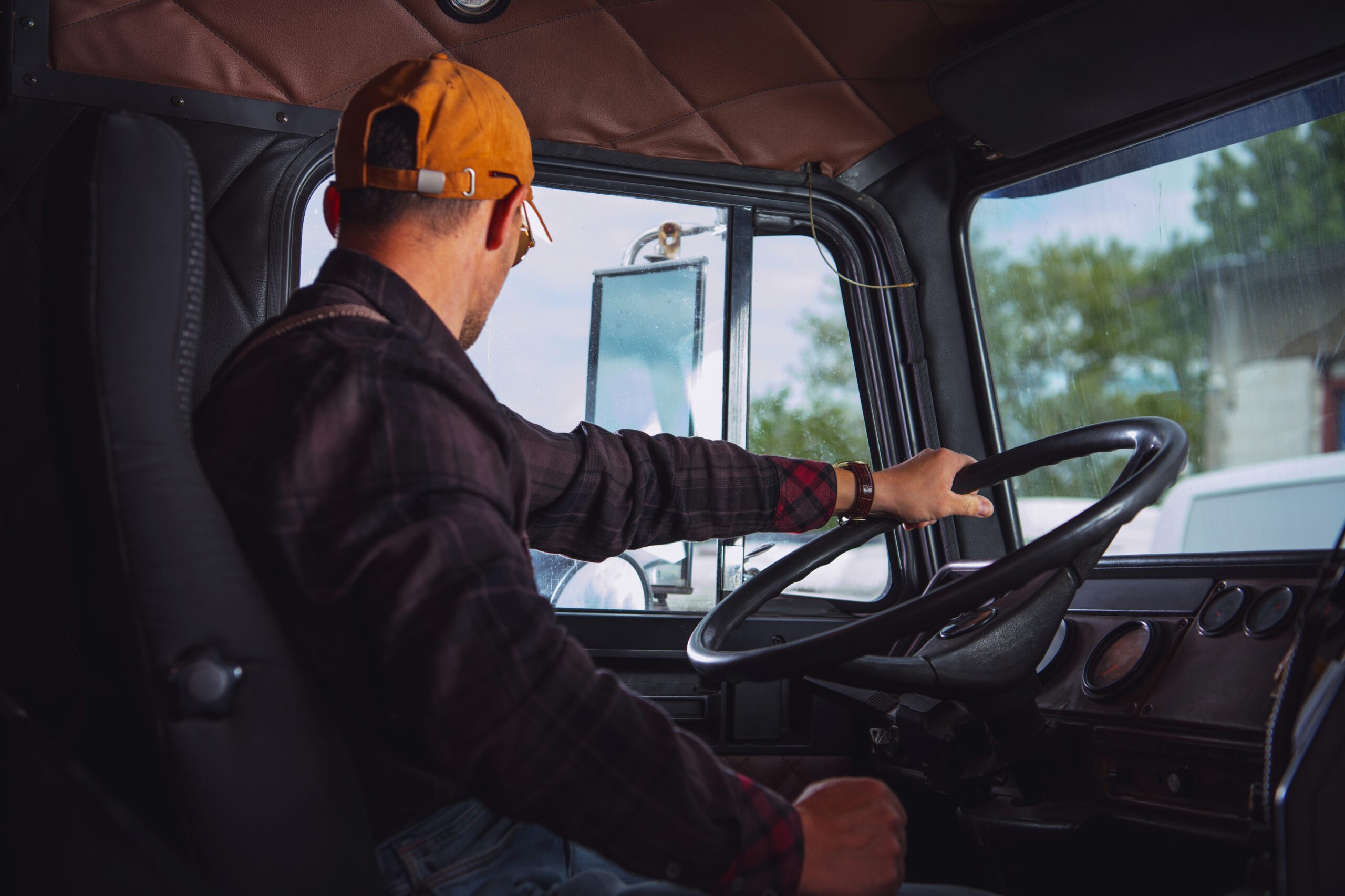 Caucasian Trucker in His 40s Inside Vintage Aged Semi Truck Tractor Cabin. Transportation Industry.