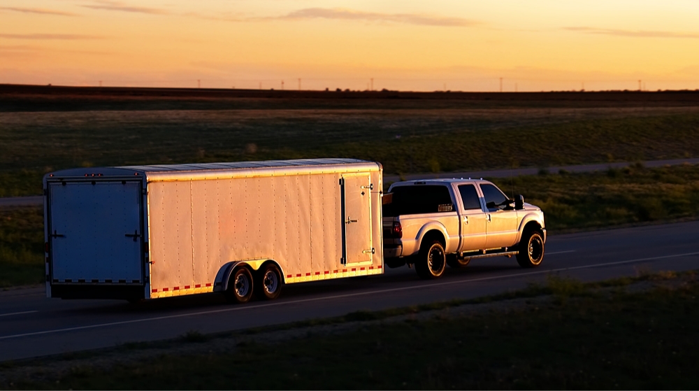 a truck driving on scenic road with a trailer at sun down